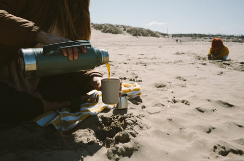 Pouring coffee from a thermos on the beach