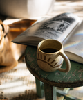 A mug of black coffee on a stool in the afternoon light