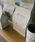 A row of HoneyCo coffee bags lined up on a wooden counter