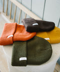 Scout Beanies in Rust, Brown, Gold and Green, stacked on a stone pedestal